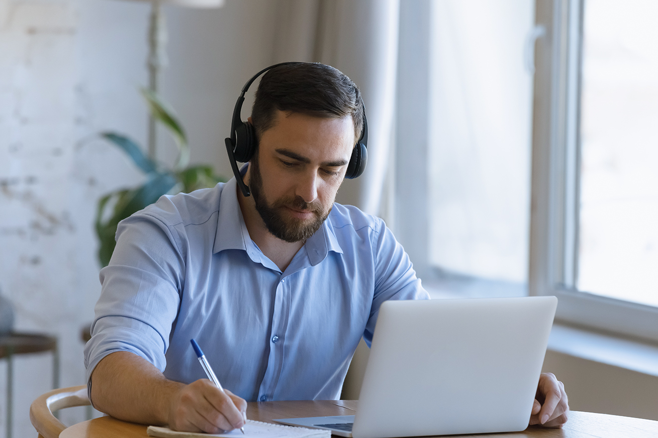 Person with headphones behind laptop